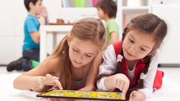 Kinder spielen auf einem Tablet die beliebtesten Online-Spiele für Kleinkinder und Vorschüler. Die Kinder befinden sich in einem hellen Kinderzimmer 